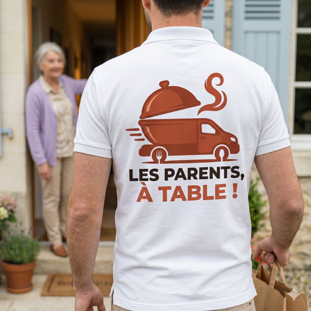 Livreur en polo Les parents, à table ! accueilli par une senior souriante sur le pas de la porte
